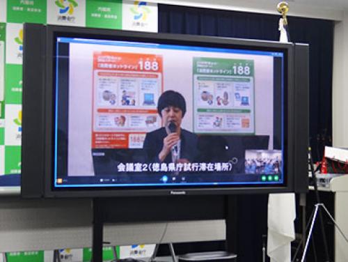 テレビ電話で会見に応じる坂東長官