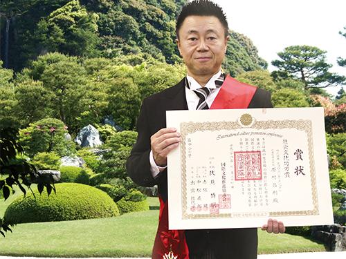 賞状を手にする原村昌利社長