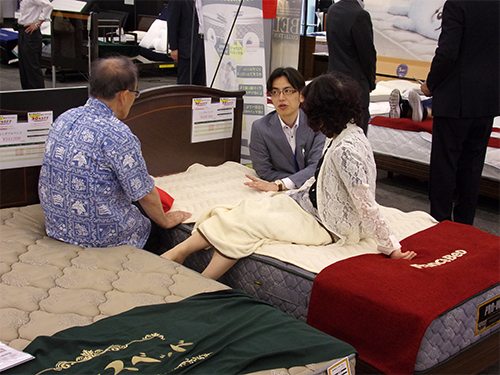 展示会で製品を説明するフランスベッド販売スタッフ