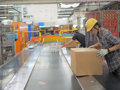 日本郵便は先進技術の活用により、ベルトコンベヤーへの荷物の積み下ろしの自動化を図る