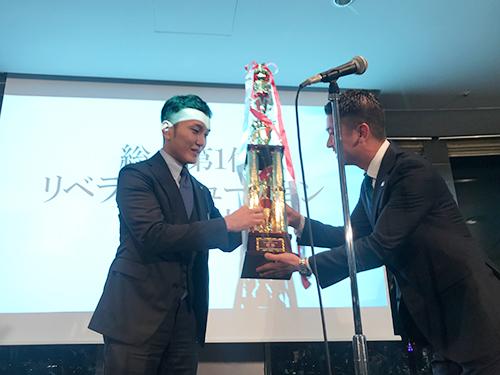 優勝トロフィーを渡す主催会社サンワシステムの苅込英二社長（右）と、トロフィーを受け取るリベラルソリューションの下田穣社長