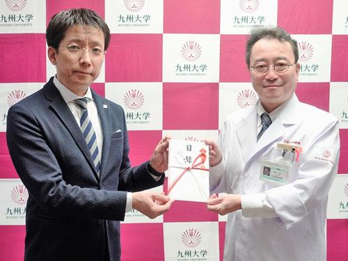 寄贈式に登壇した新日本製薬の後藤孝洋社長（左）と九州大学病院の赤司浩一病院長